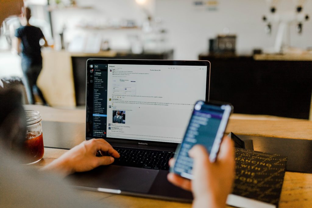 A person uses a computer and phone simultaneously