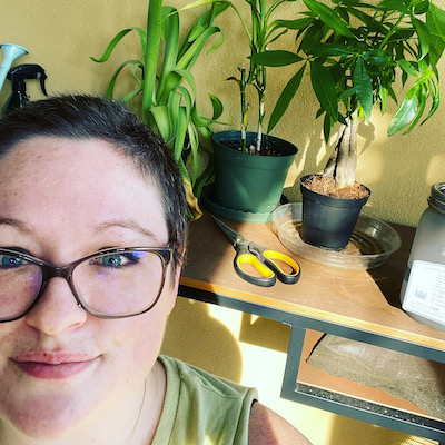 CJ stands in front of a table covered with houseplants